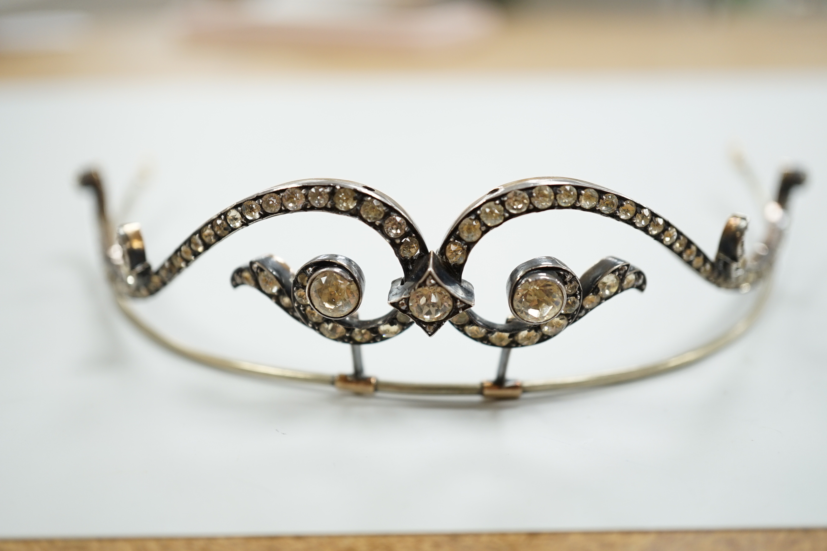 A 19th century, white and yellow metal paste cluster set tiara, width 13cm, the central stone with rose cut diamond chip spacers.